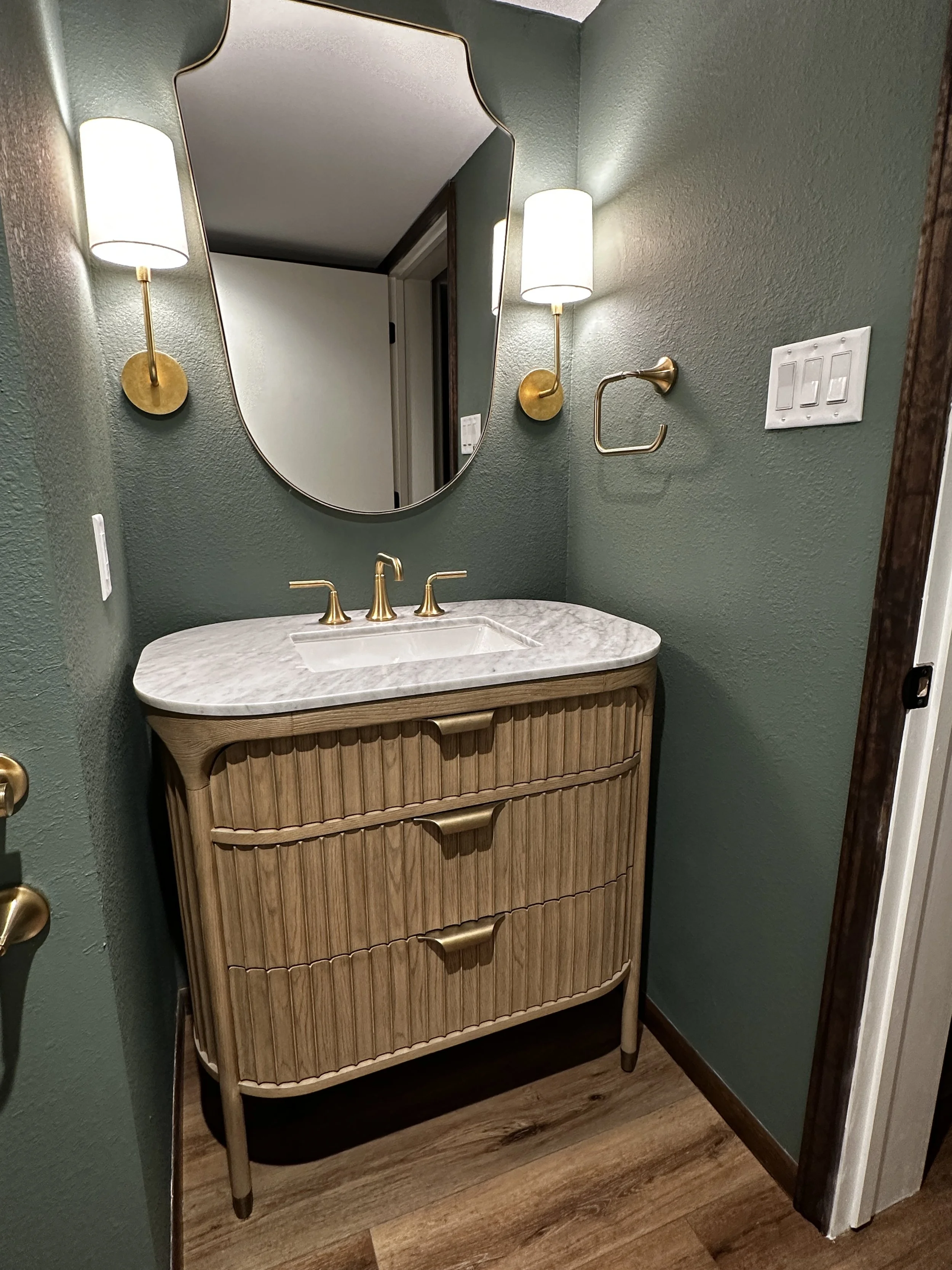 Elegant new powder room in a San Antonio home featuring sophisticated wallpaper and light finishes, repurposed from a former hallway closet.