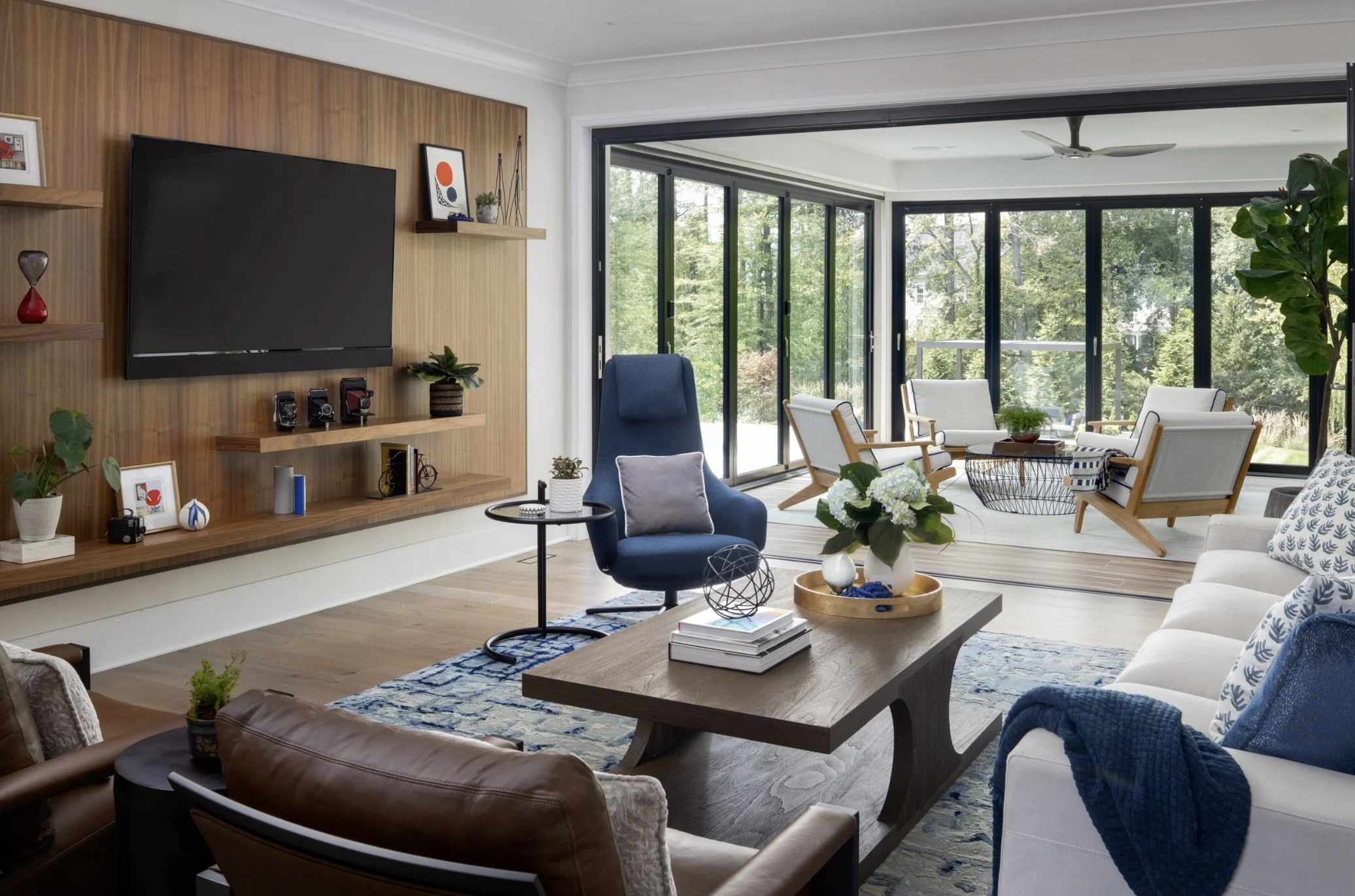 Open concept interior design showing the flow between a luxury living room and sunroom with expansive windows and natural sightlines.