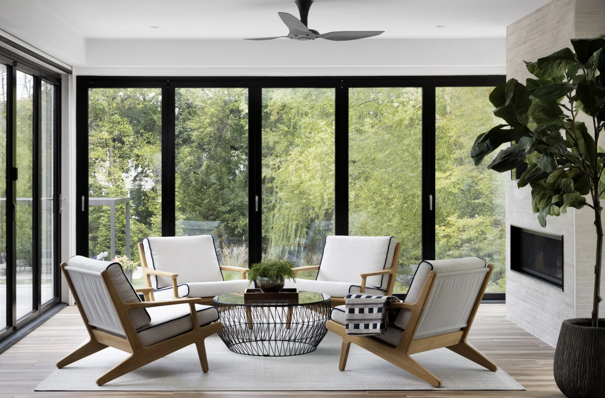 Luxury sunroom design featuring teak lounge chairs arranged in radial symmetry to create a central focal point in a Northern VA home.