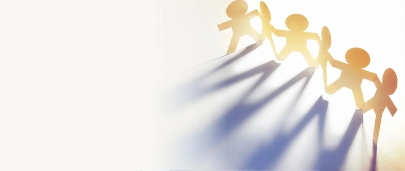 Papierfiguren in der Form von Menschen halten sich an den Händen und bilden einen Kreis, Schatten auf weißem Hintergrund