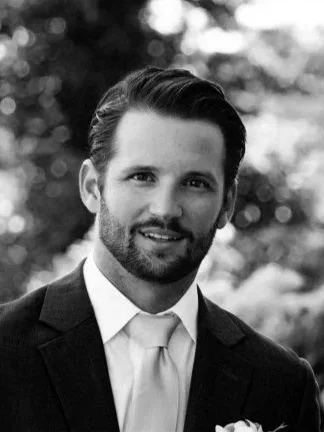 A black and white portrait of Joseph A. Pasquale, president of Southpaw Capital, in a suit and tie, outdoors with blurred trees in the background.