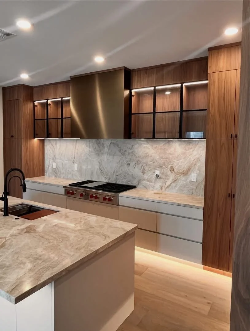 Modern kitchen with marble countertops, wooden cabinets, a black faucet, and a stainless steel range hood over a stove.