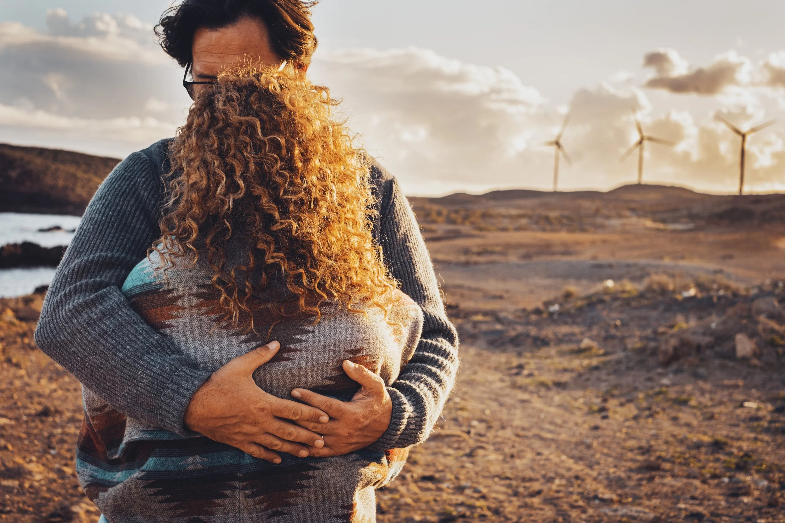 Image: A couple embracing in a barren landscape. The image suggests the idea from the population decline SparkMap that human fertility rates may be suffering due to environmental toxins.