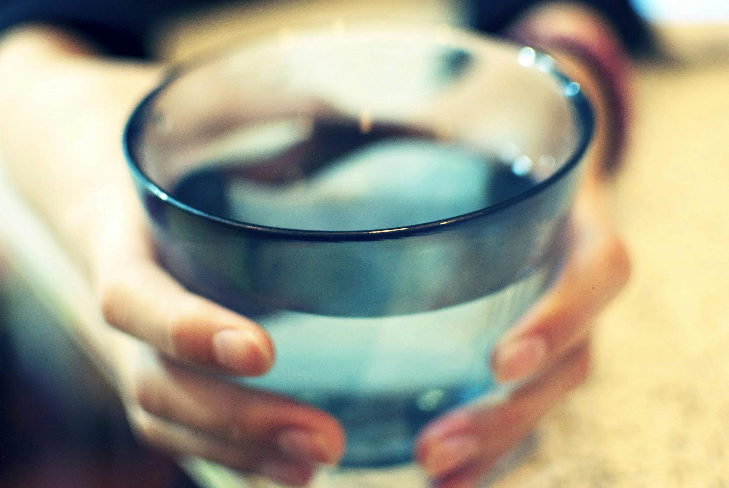 hands cupping a blue glass with water representing healing for therapists