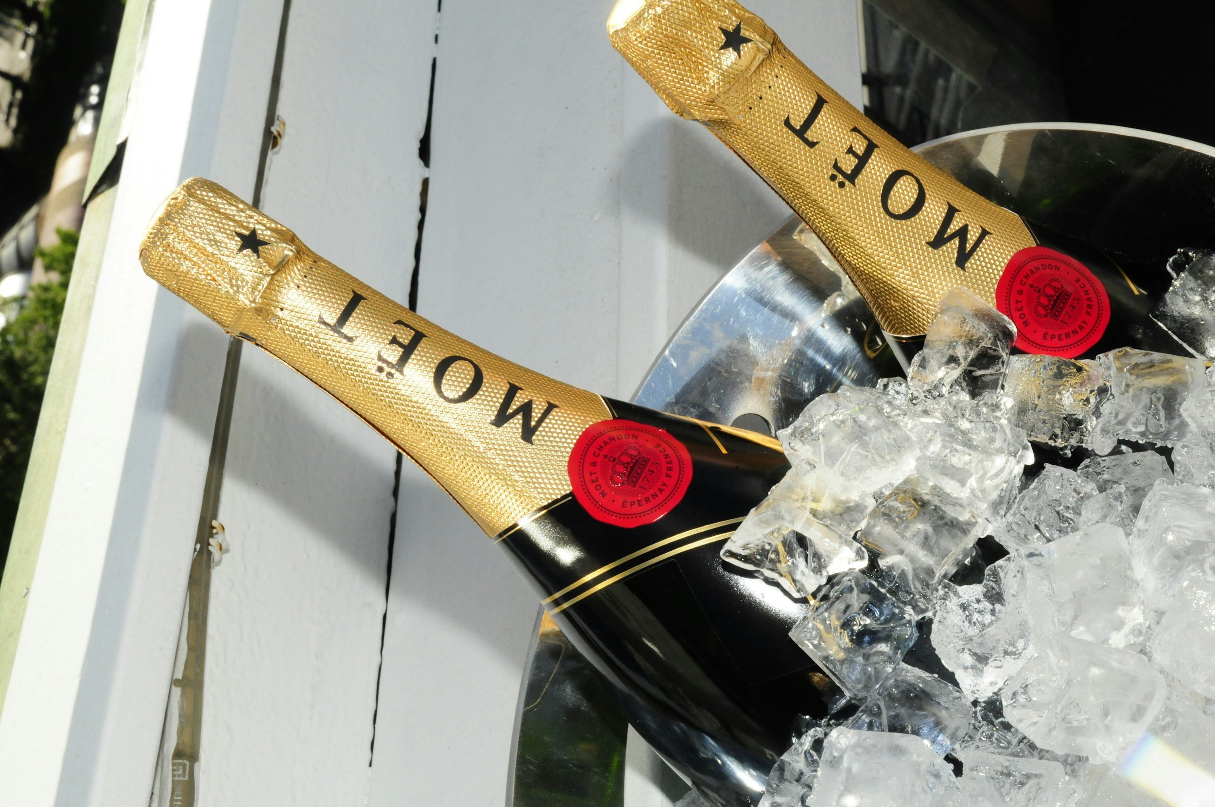 Two bottles of Moët & Chandon champagne chilling in a metal ice bucket with ice cubes.
