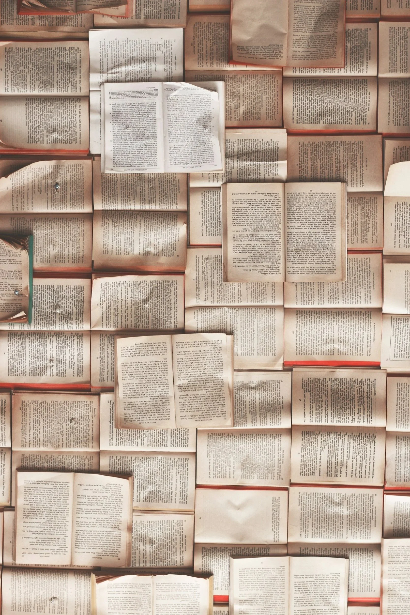 A collection of open books and pages arranged on a flat surface, creating a textured background with various texts visible.