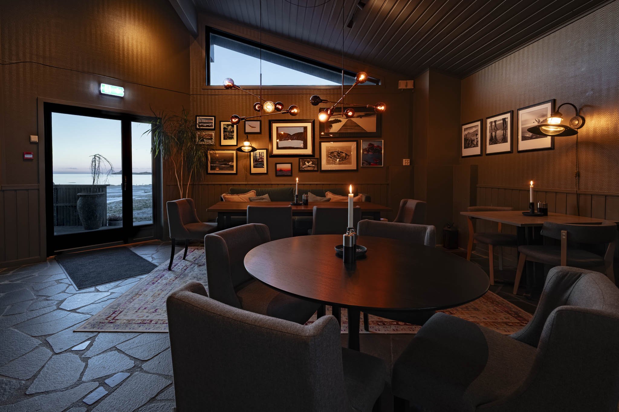 Cozy restaurant interior with framed artwork on the wall, candles on the tables, and modern pendant lighting.