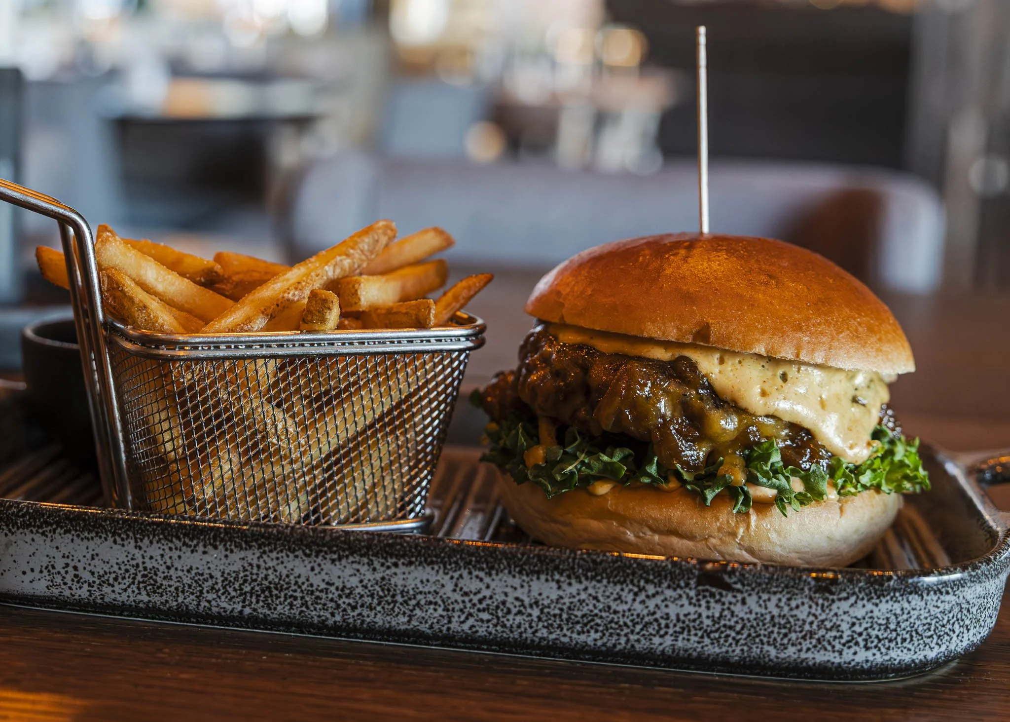A plated gourmet dish featuring a chicken breast topped with herbs, served with roasted vegetables and garnished with fresh herbs.