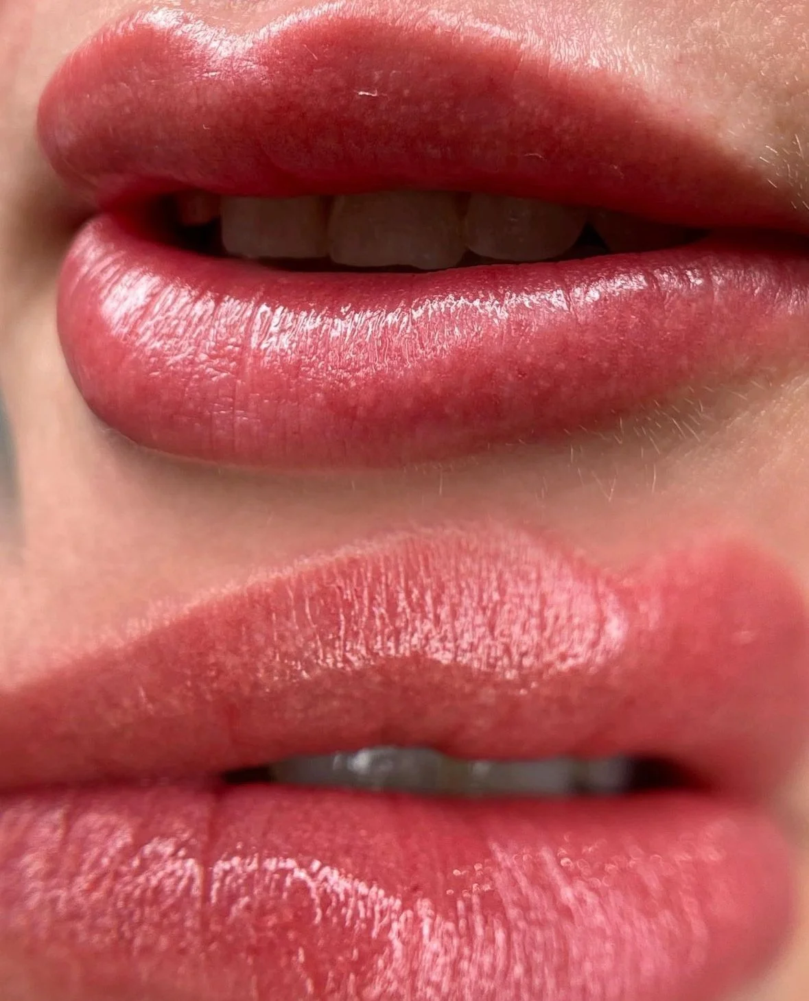 Close-up of lips with glossy pink lipstick.