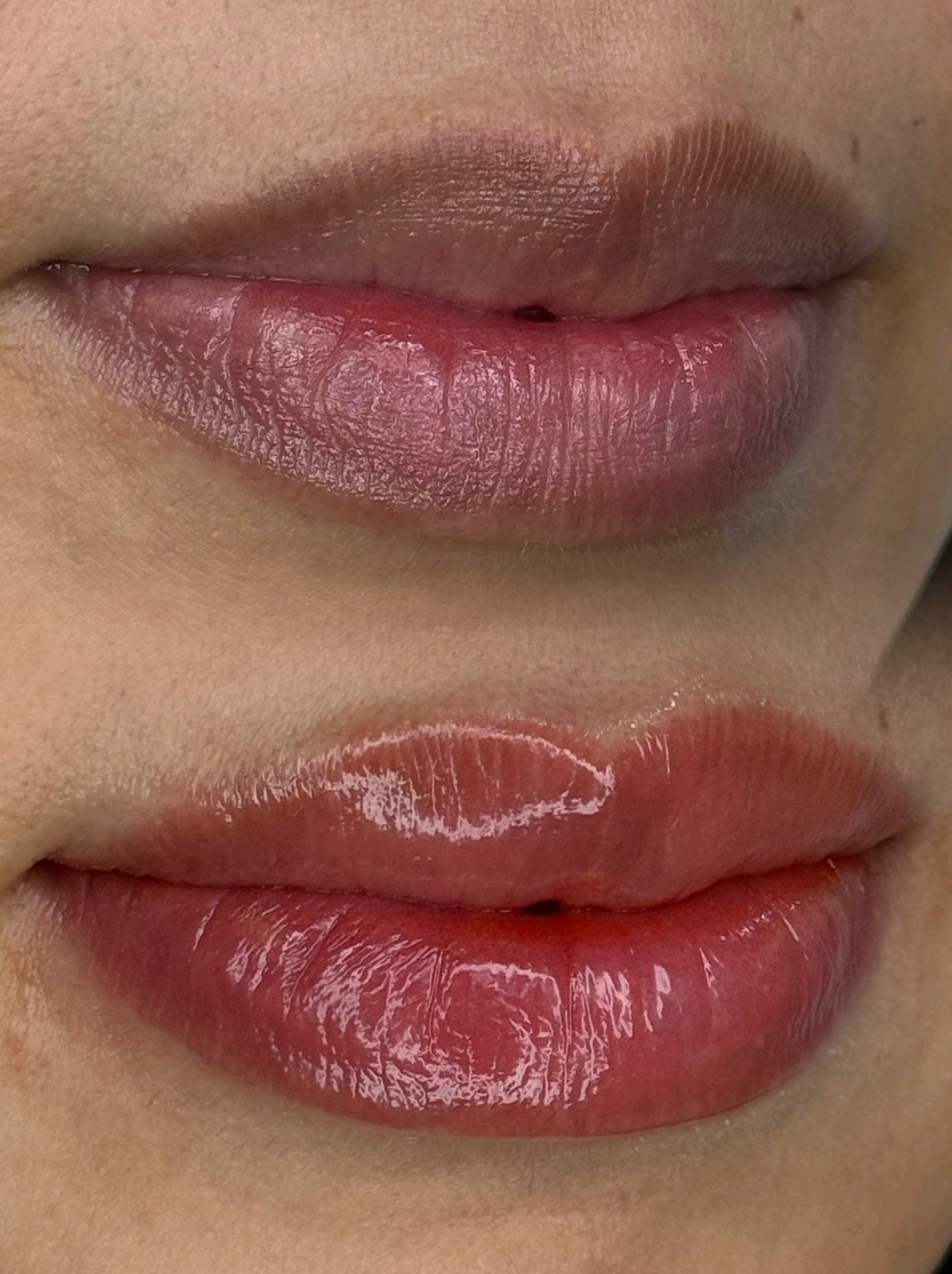 Close-up of lips showing before and after applying clear lip gloss; top lips are matte, and bottom lips are glossy.