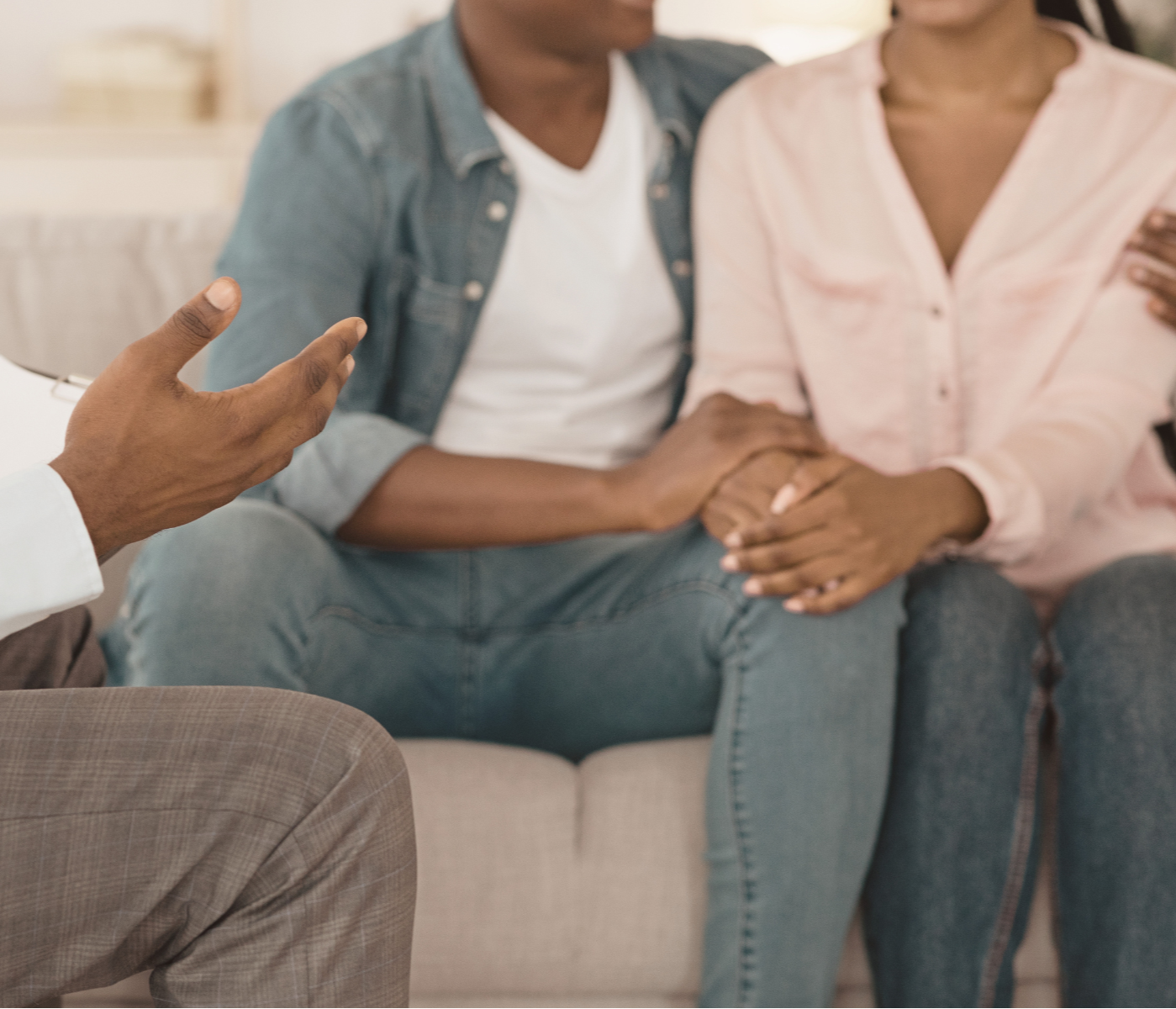 African American Couple holding hands while talking with a therapist during a couples counseling session.