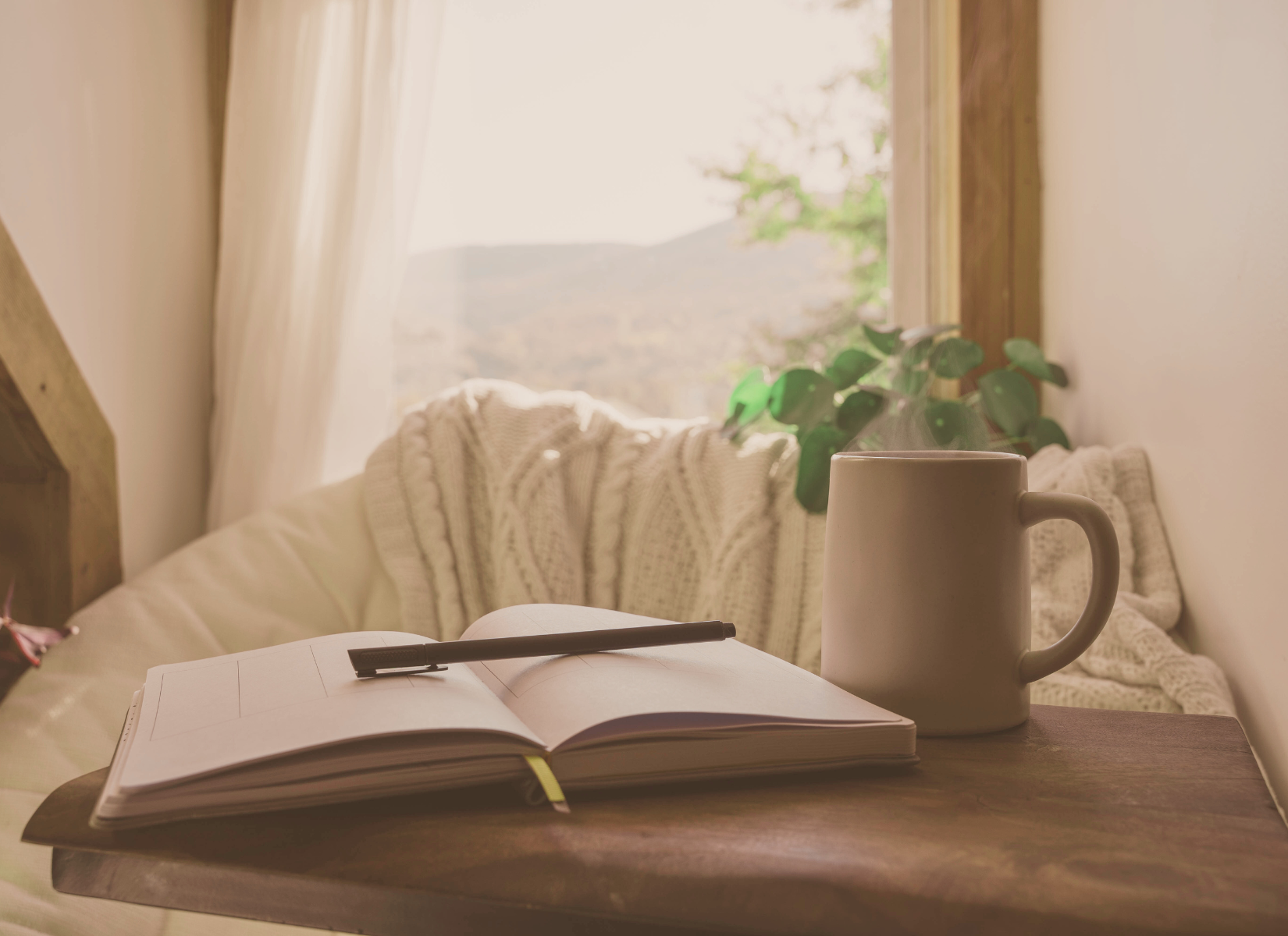 Open journal and warm mug beside a sunlit window.
