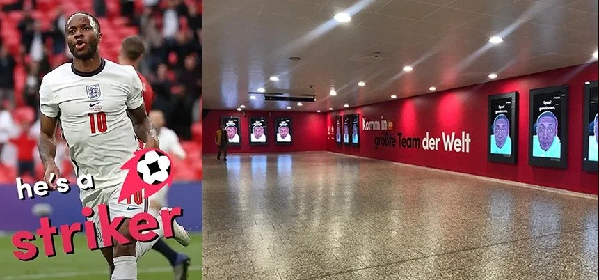 A large indoor area with a red wall displaying digital screens, and a person walking in the hallway. Also includes an overlay with a soccer player in an England jersey and text that says 'he's a striker'.