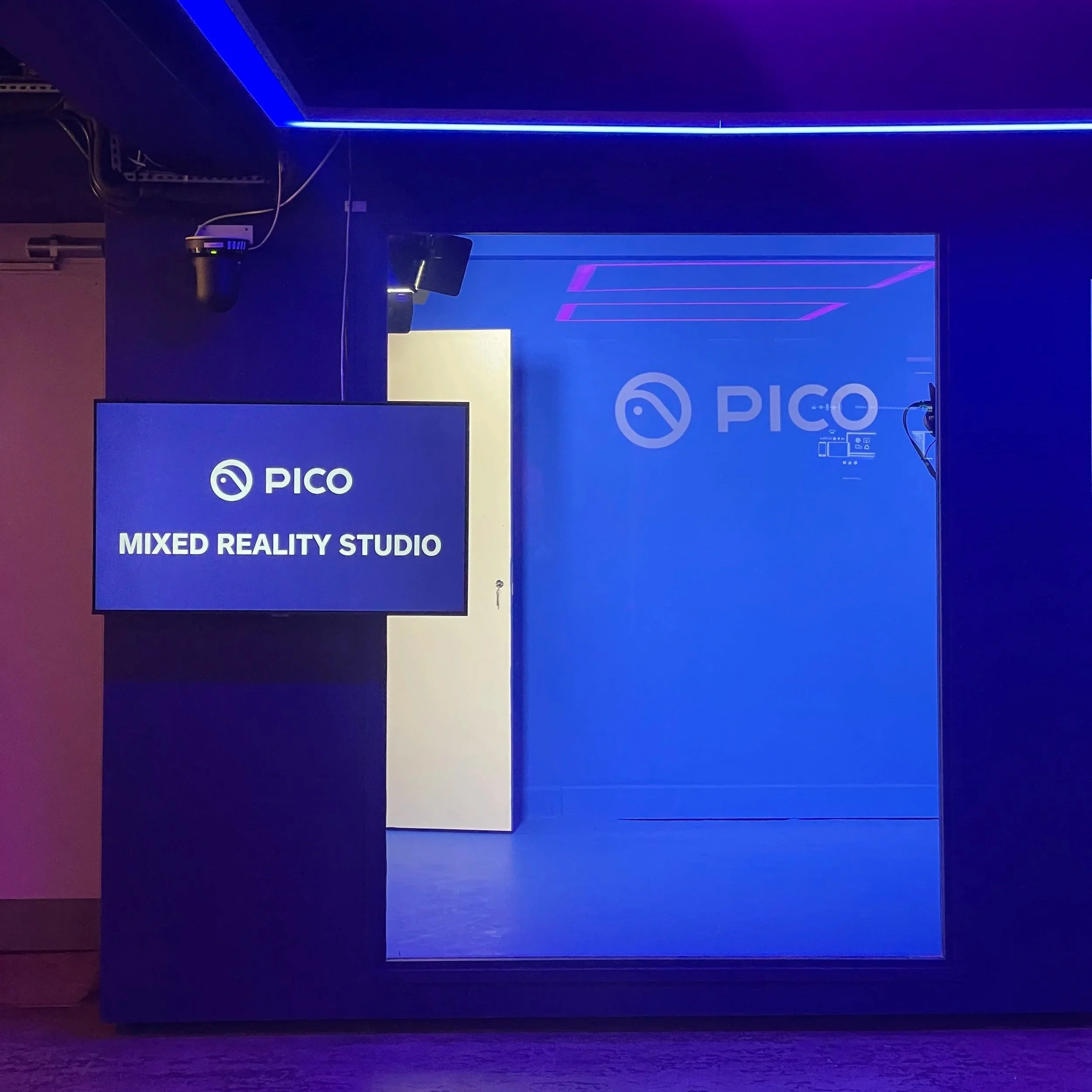 Entrance to PICO Mixed Reality Studio with a blue-lit door, a hanging sign displaying 'PICO' and 'MIXED REALITY STUDIO'
