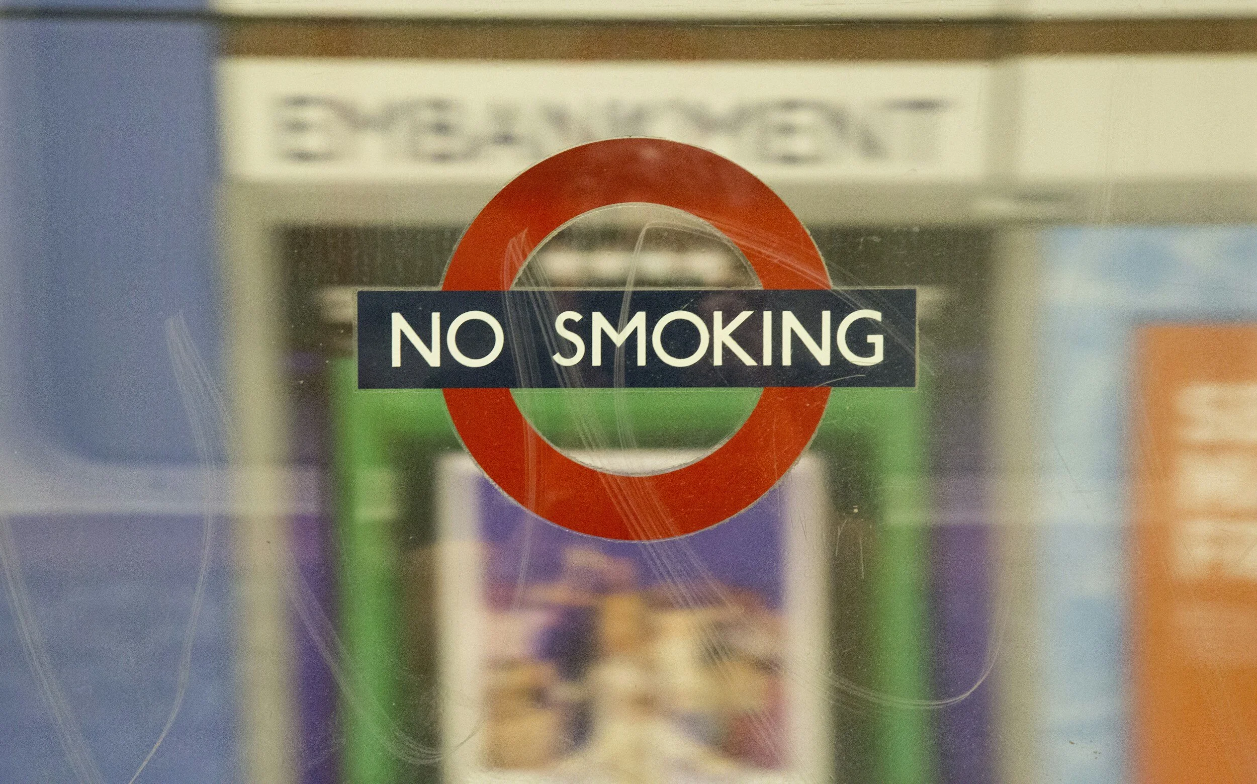 Glass door with a circular red no smoking sign and black rectangular sign that reads 'NO SMOKING'