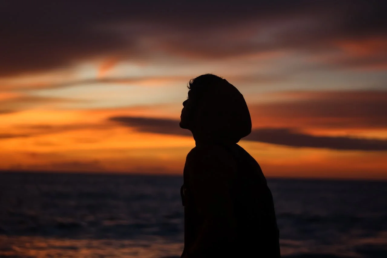silhouette-of-person-in-hoodie-on-beach-during-sunset