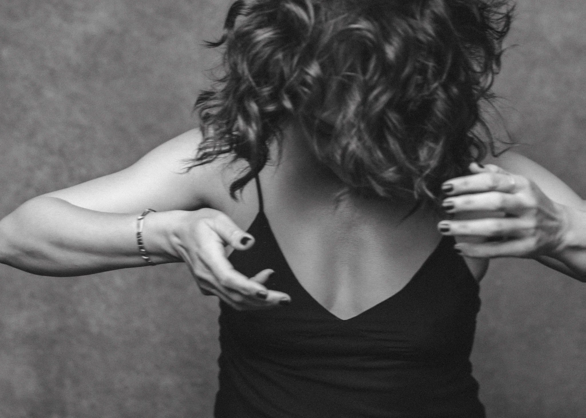 black and white picture of a brunette woman shaking her hair with her hands 