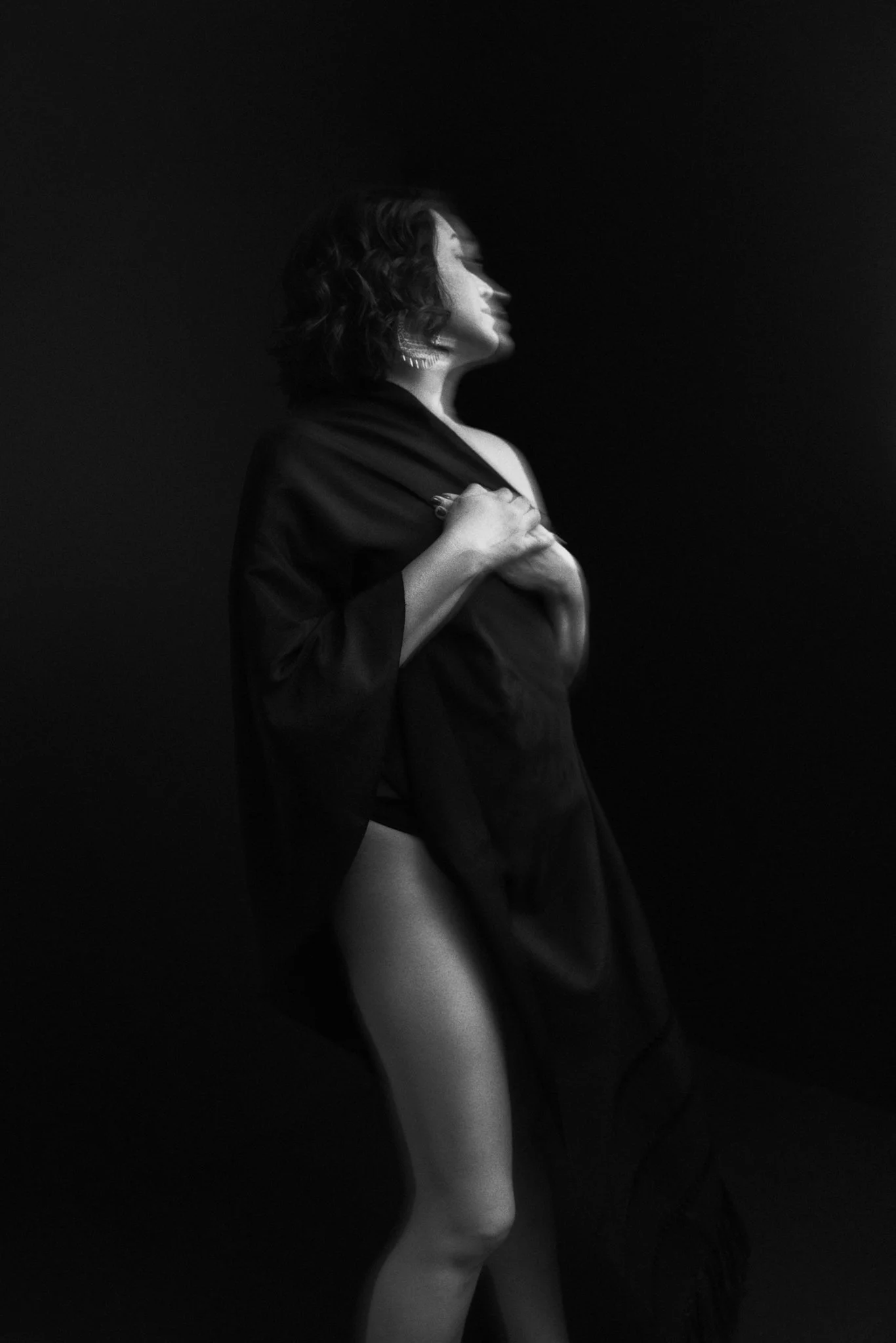 Woman wrapped in a black sarape with her hands over her heart with some movement blur