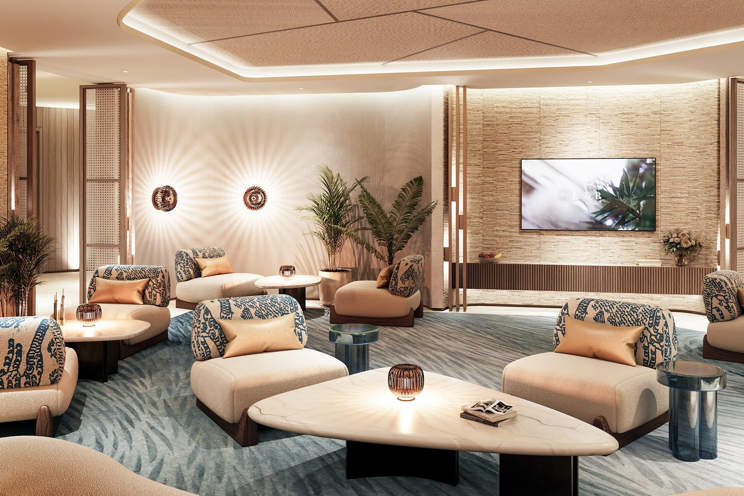 Modern hotel lobby with beige and blue patterned chairs, white marble coffee tables, and large potted plants. A large flat-screen TV is mounted on a textured wall with warm lighting.