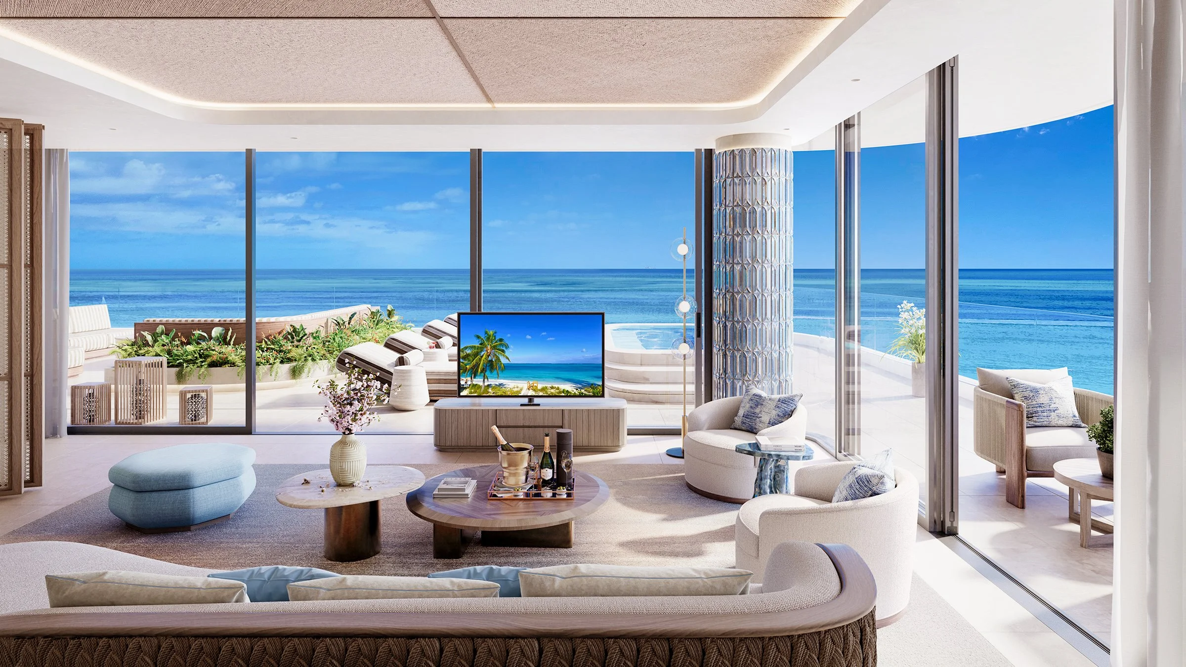 Living room with large windows overlooking blue ocean, featuring white lounge chairs, a TV, and indoor plants.