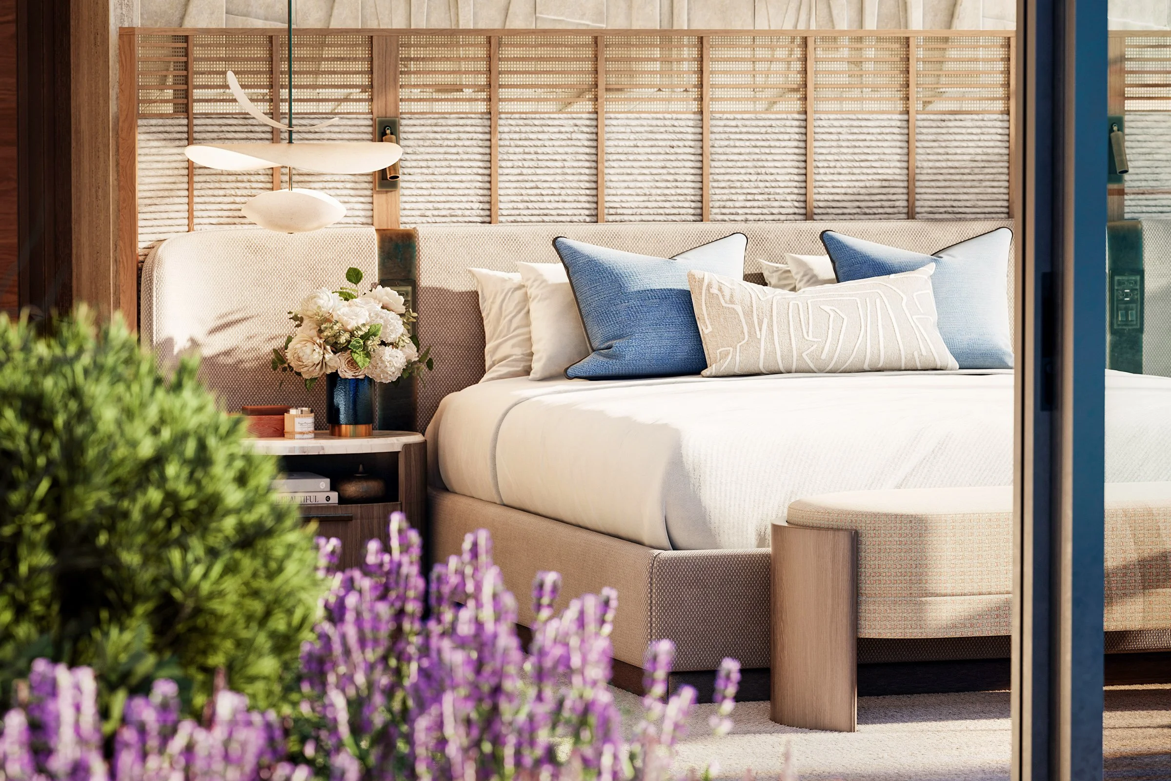 A cozy bedroom with a large bed, decorative pillows, a bedside table with a vase of flowers, and a textured headboard with wood framing. The room features natural light and a serene, neutral color palette.