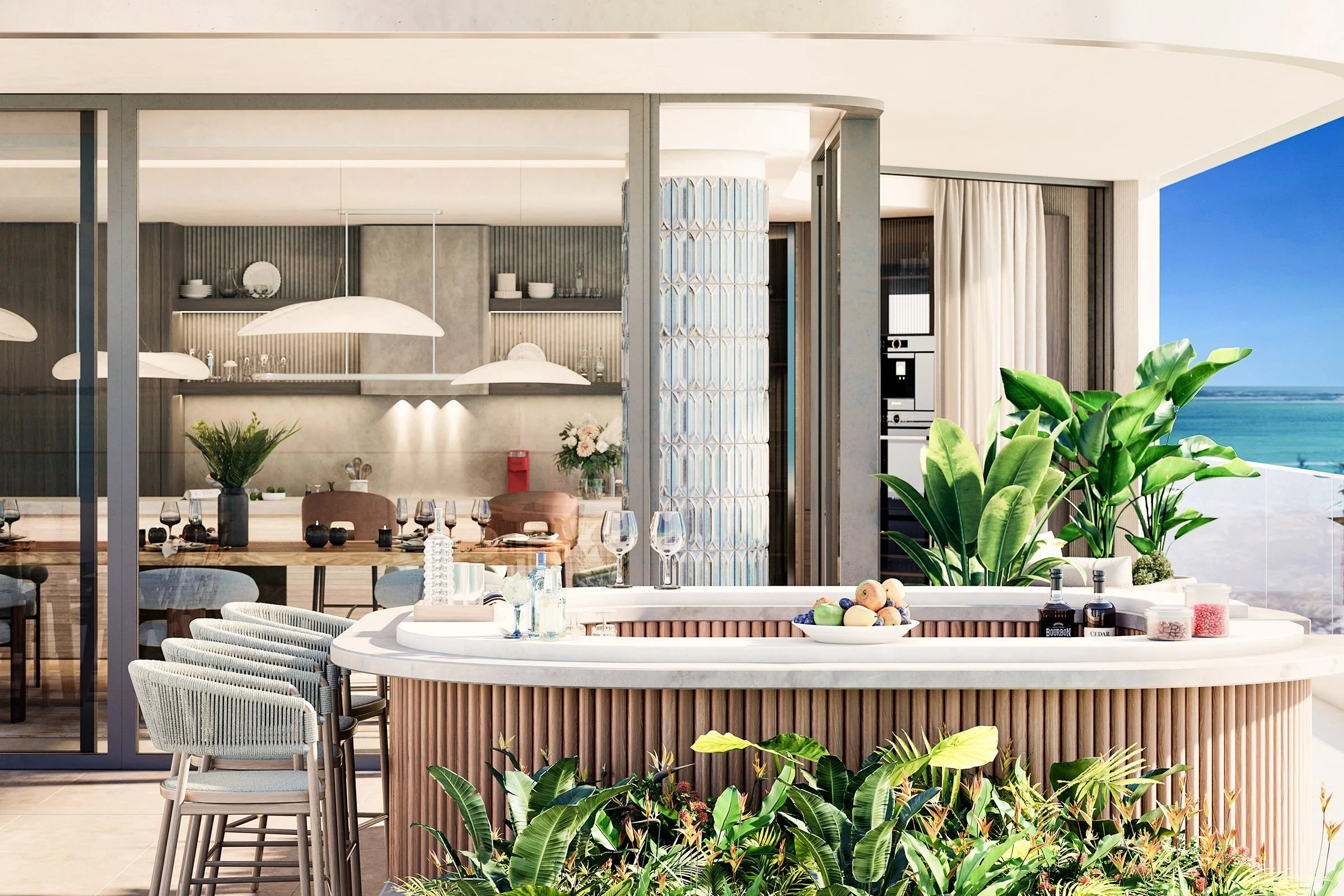 A modern outdoor dining and kitchen area with a view of the ocean, featuring a white countertop bar with fresh fruit, drinks, and plants, surrounded by lush greenery and seating.