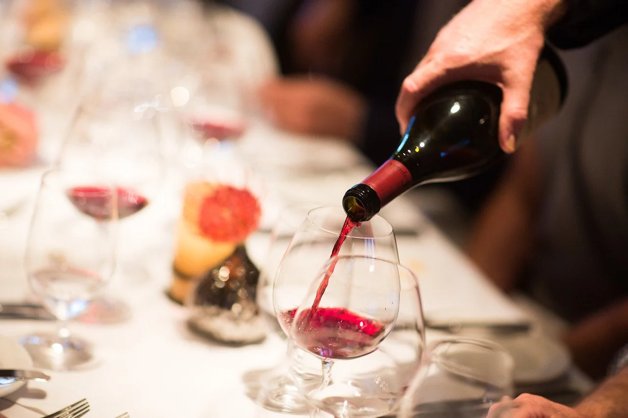 Red wine pouring into glass on large table