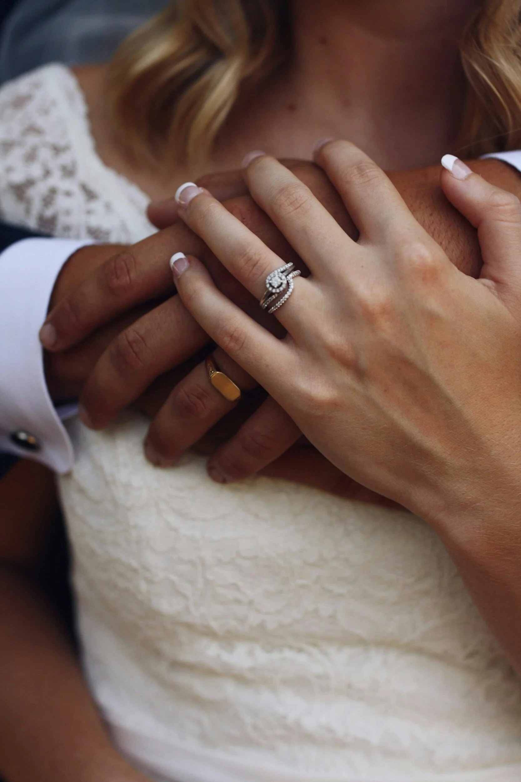 Bride and groom holding hands with diamond engagement ring, symbolizing a custom love story