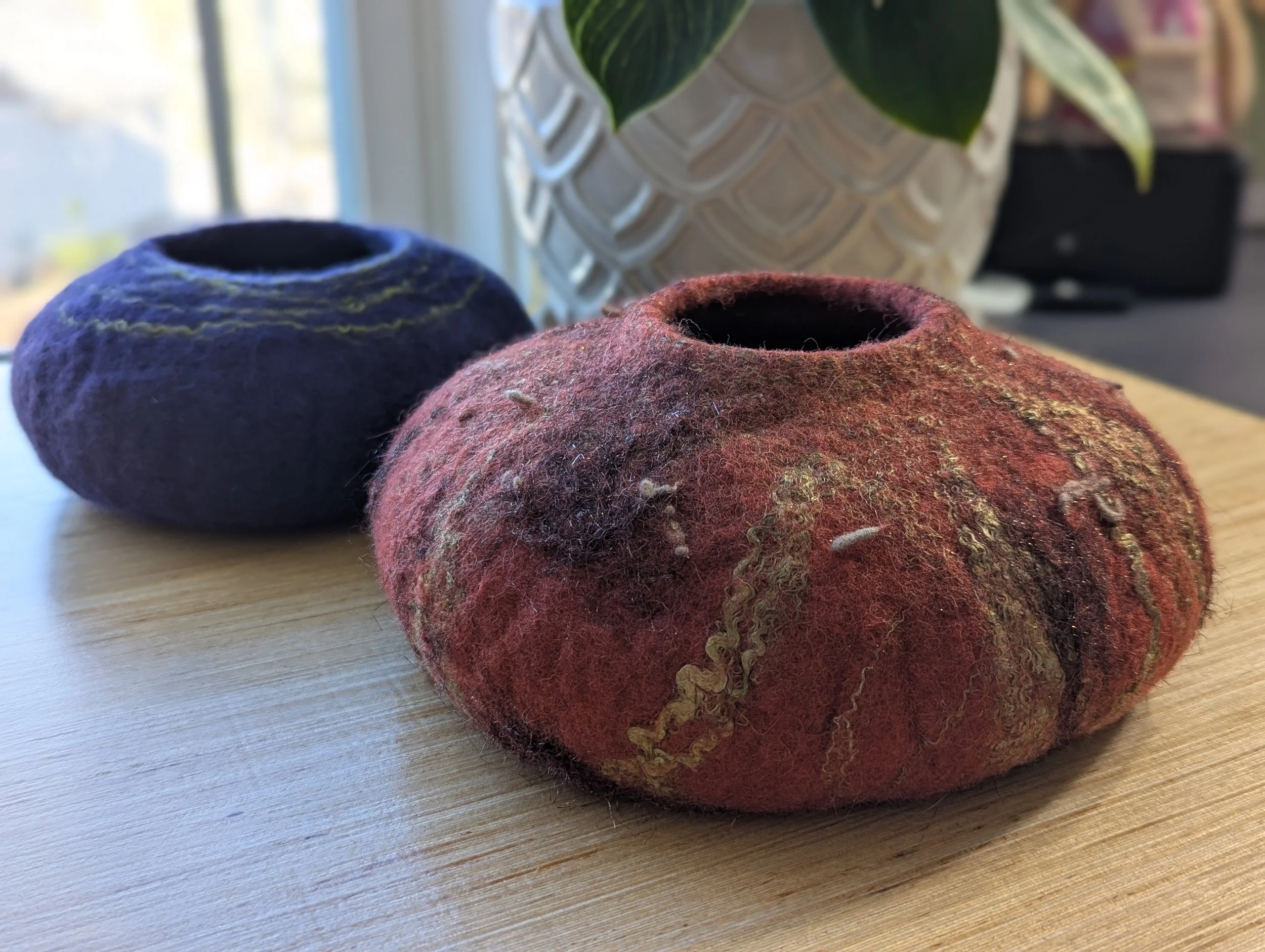 two wet felted vessels, one brick orange with gold threads felted in and one blue