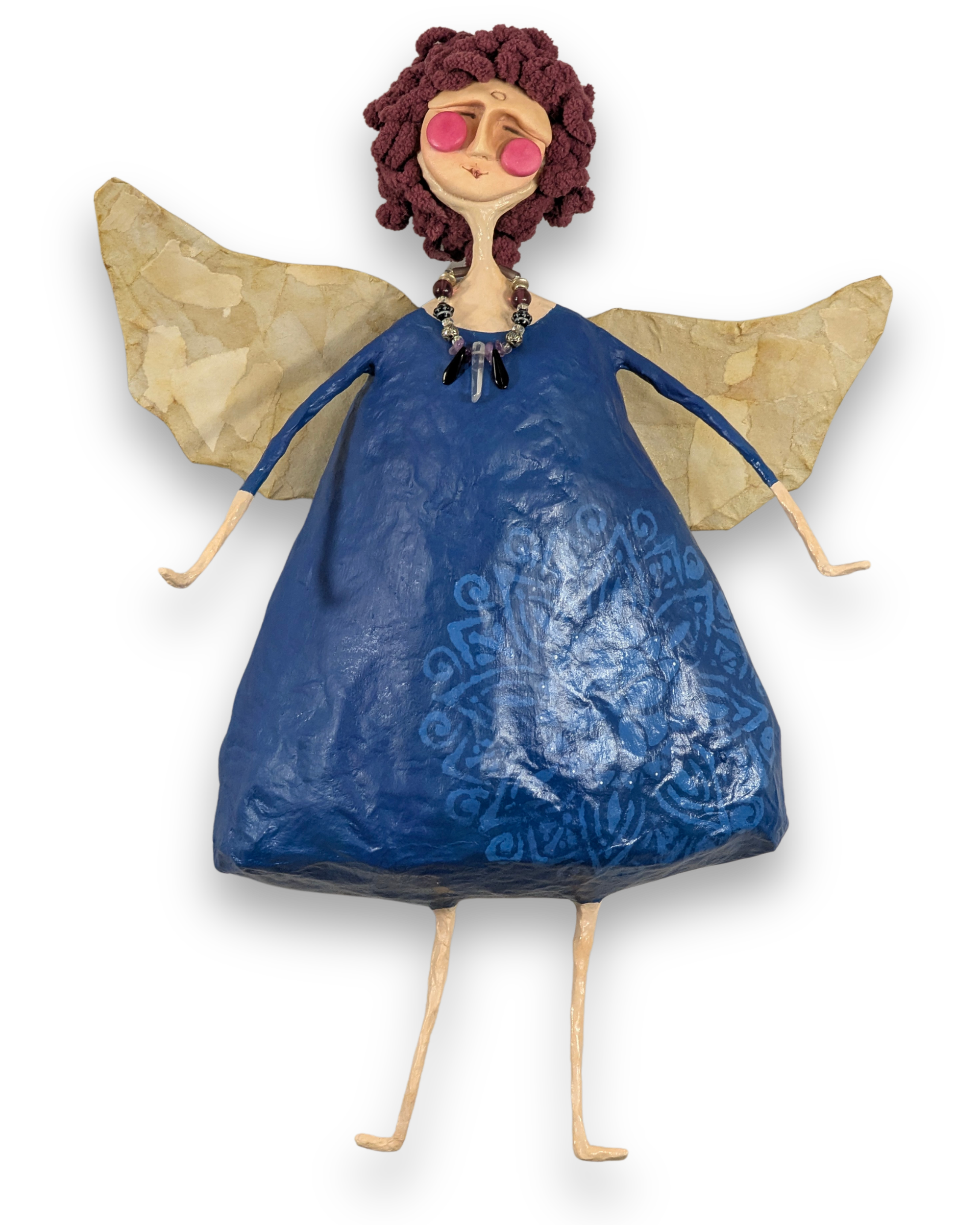 Betty, a handmade papier-mâché angel with purple curls, a deep blue patterned dress, crystal necklace and wide golden wings.