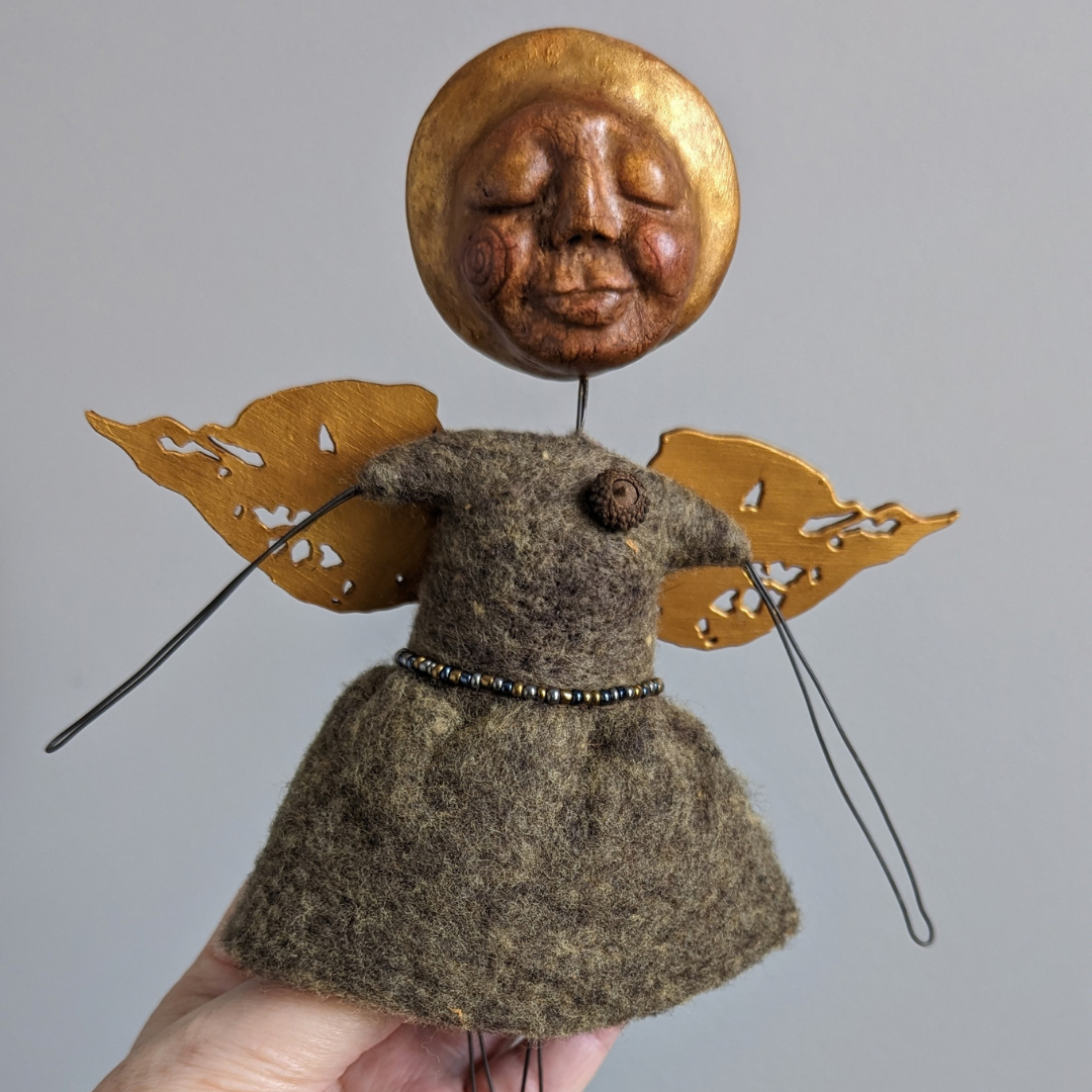 Finished felted spirit doll with a handmade clay face, wire arms, and gold wings.