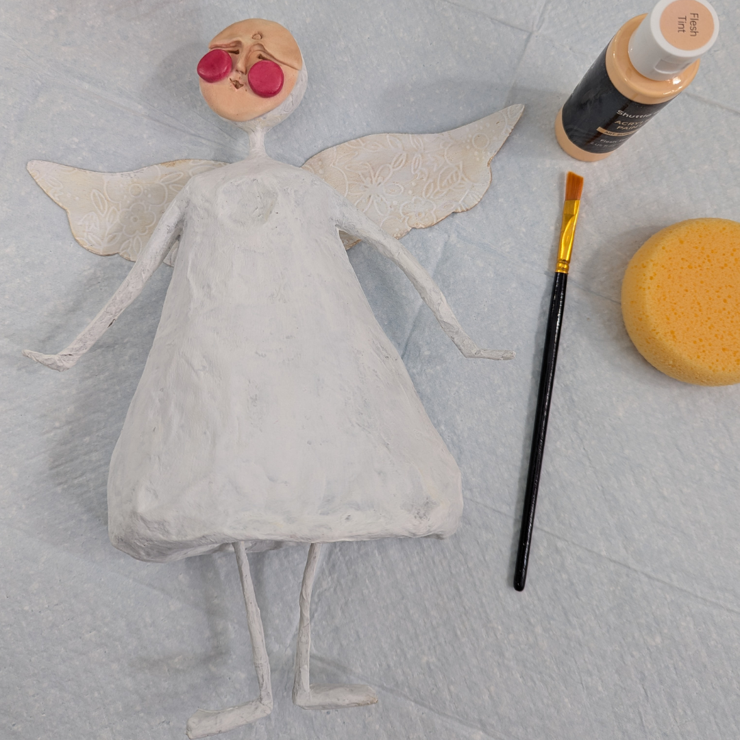 Papier-mâché angel with clay face and textured wings ready for paint.