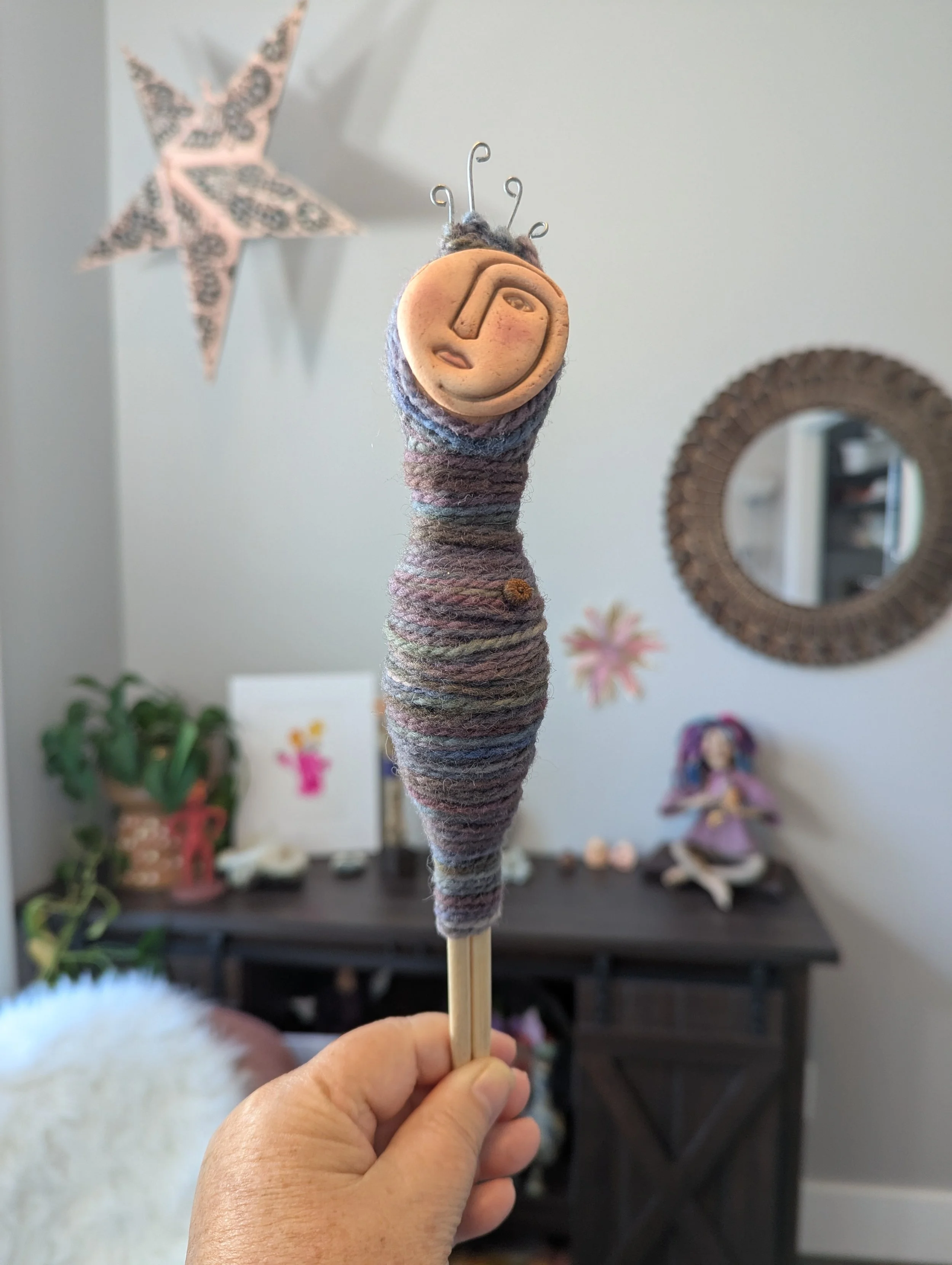 Handmade Bundle Doll wrapped in multicolored yarn with a clay face and curled wire details.