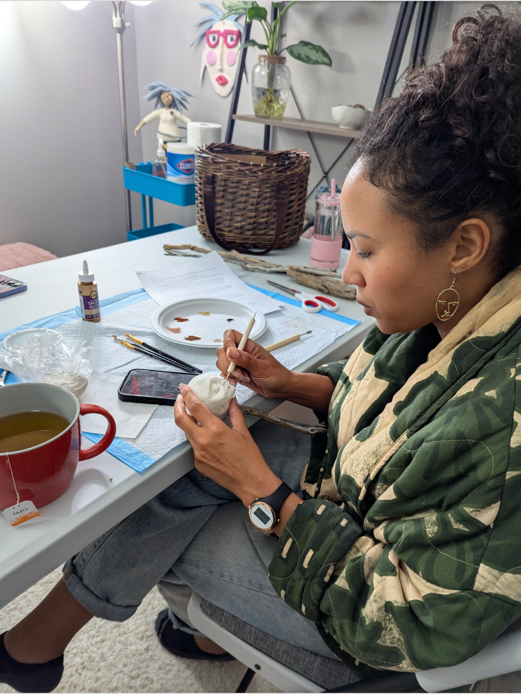 a woman sitting at a table creating a clay face for a spirit doll during a spirit doll retreat in asheville