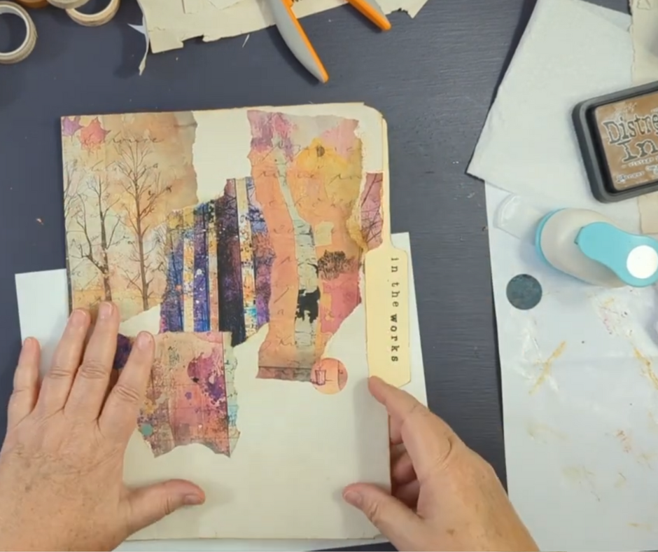 Hands holding a handmade collage folder created from painted and printed paper, part of a simple intuitive art project.