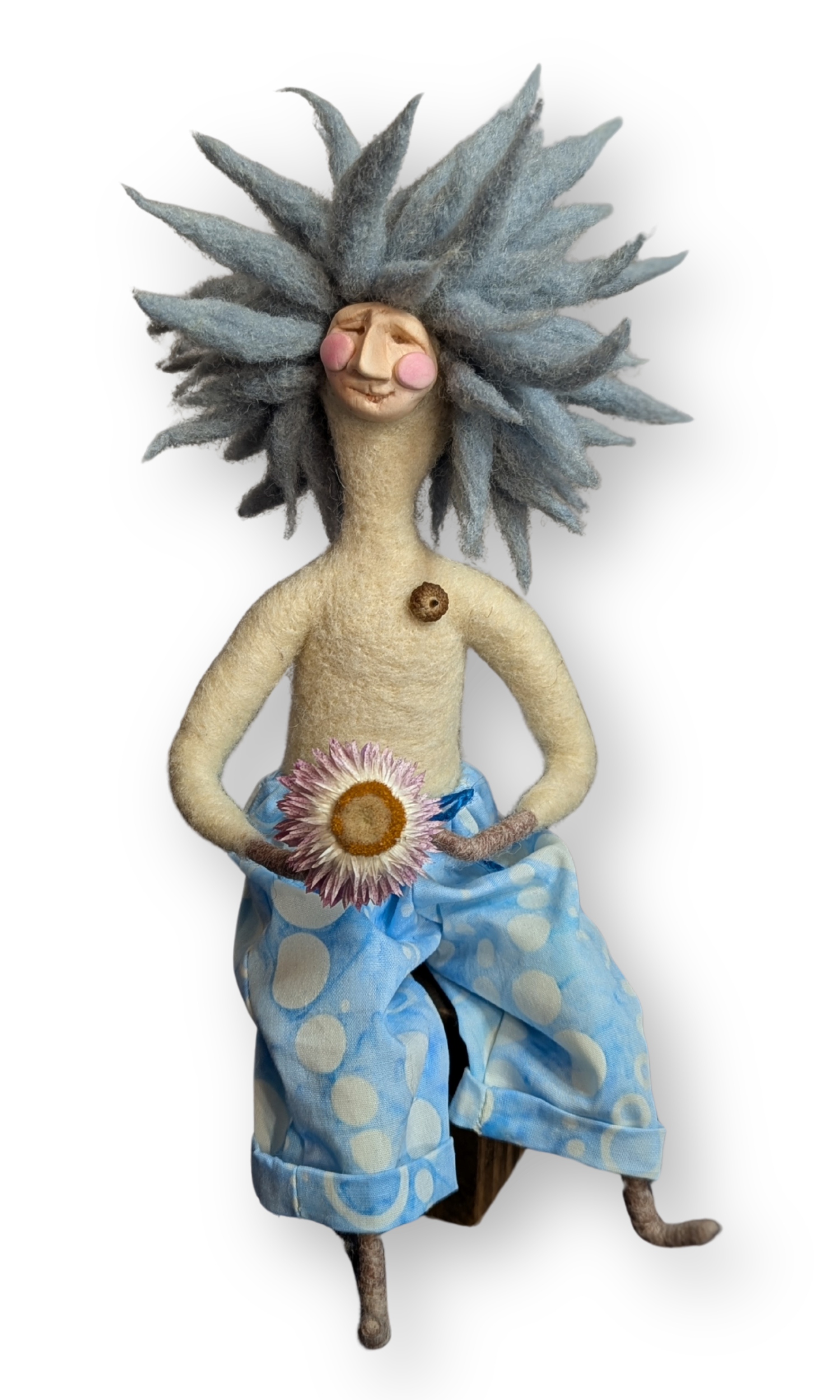 Front view of Surfer Dude Guardian Doll — handmade needle-felted art doll with blue wool hair, flower, and polka-dot pants sitting on a wood block.