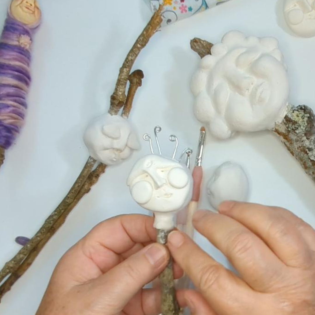 Hands shaping a whimsical face from white Model Magic clay for a spirit doll.