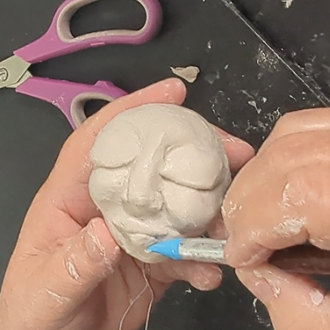Adding and shaping the mouth on a handmade clay face.