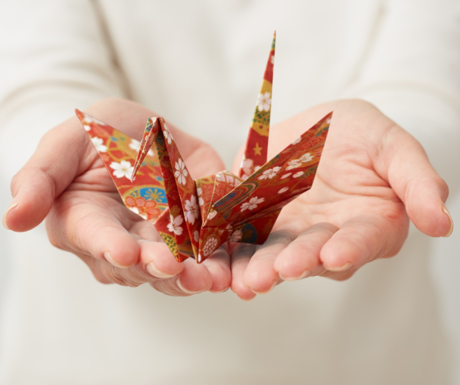 Hands gently holding a folded origami crane, symbolizing intention, care, and a creative ritual for the year ahead.