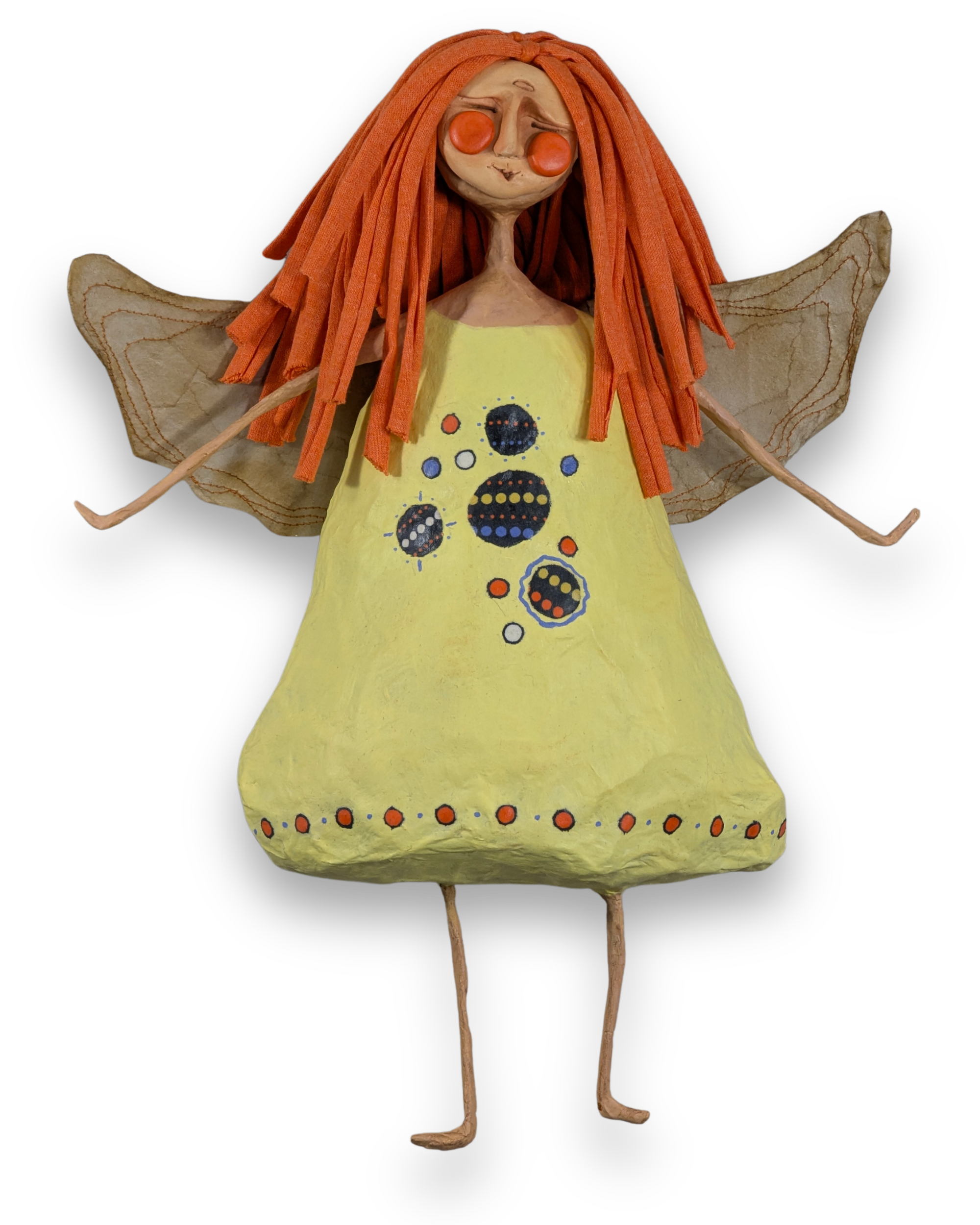 Cleo, a handmade papier-mâché angel with orange hair, a pale yellow dress decorated with colorful circles and golden wings.