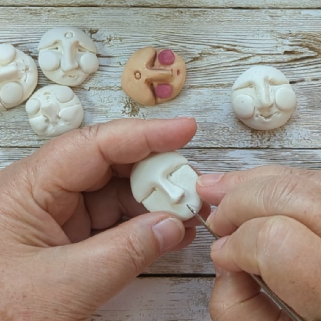 Sculpting a simple face from white Model Magic clay with a small tool.