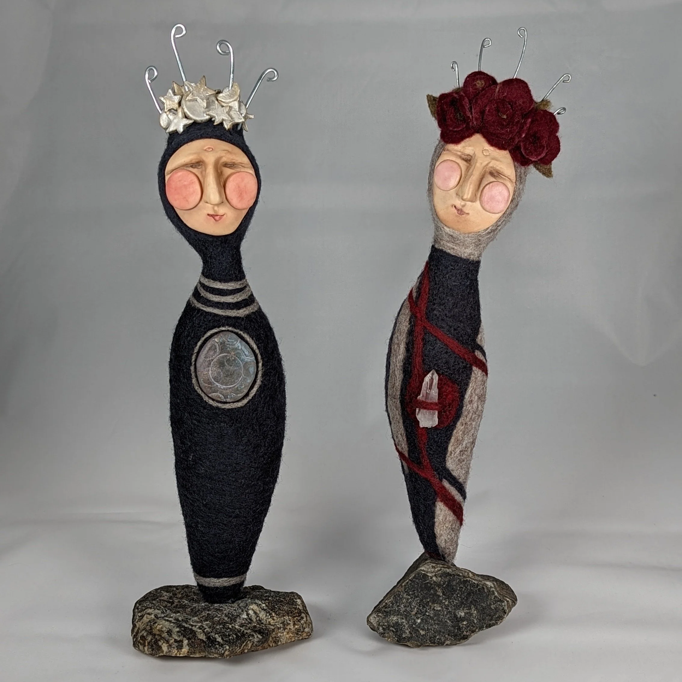 Two handmade spirit dolls with clay faces, felted wool bodies, wire crowns, crystals, and stone bases. Made by Stacy Vajta