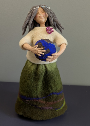 Handmade spirit doll holding a small globe representing connection to the earth.