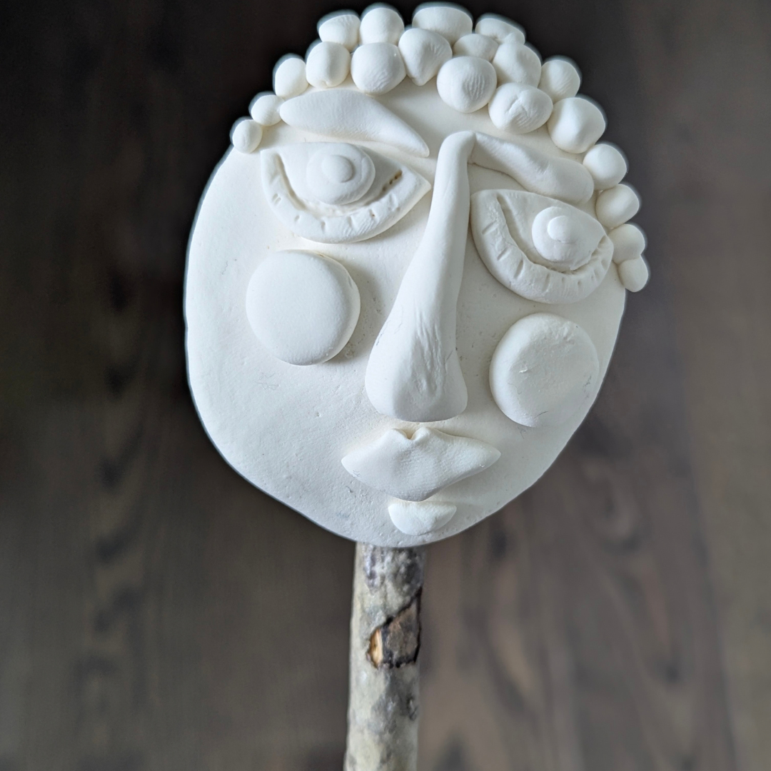 Finished whimsical face made from white Model Magic clay with exaggerated features.