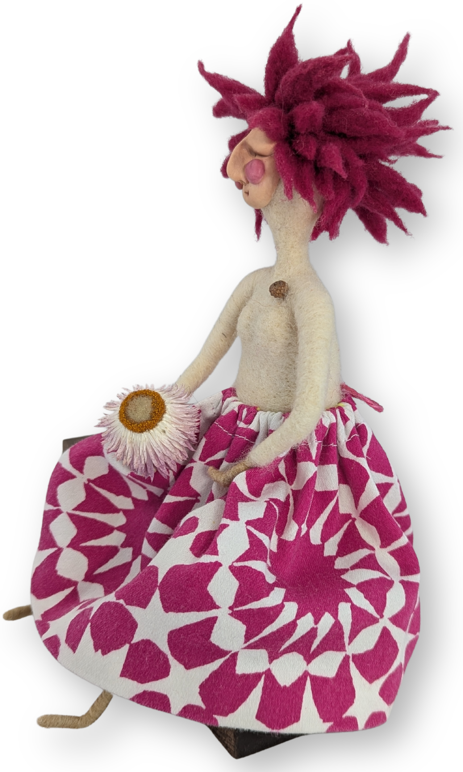 Left angle view of Flower Power Guardian Doll, a one-of-a-kind handmade doll holding a dried flower and sitting on a wood block.
