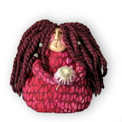 Handmade red poppet doll with long yarn hair, softly stitched face, and a dried flower tucked in her hands.