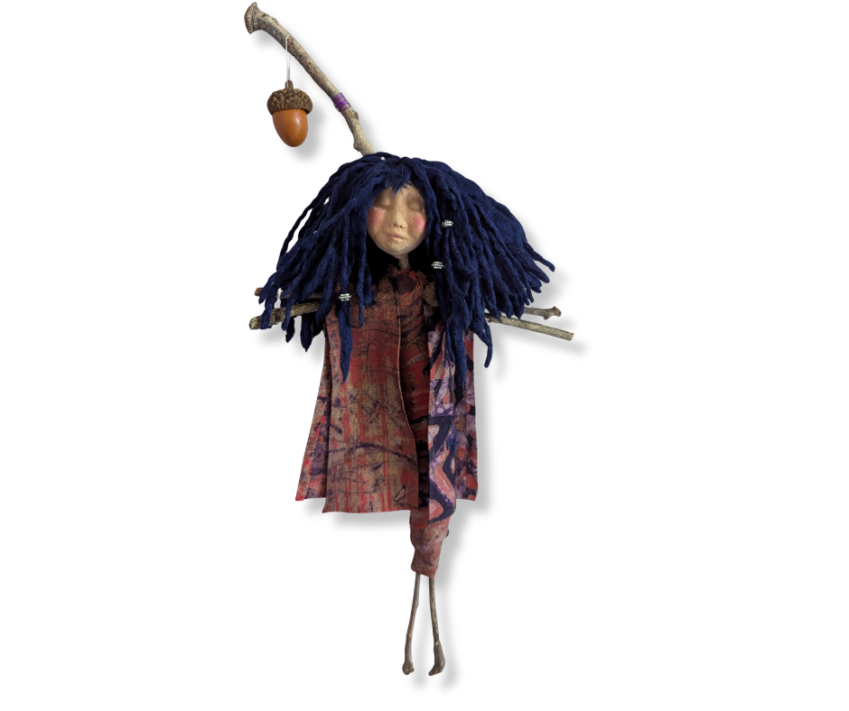A handmade stick doll with bright blue hair, a sweet sculpted face, and a small acorn hanging from the top of her wooden form.