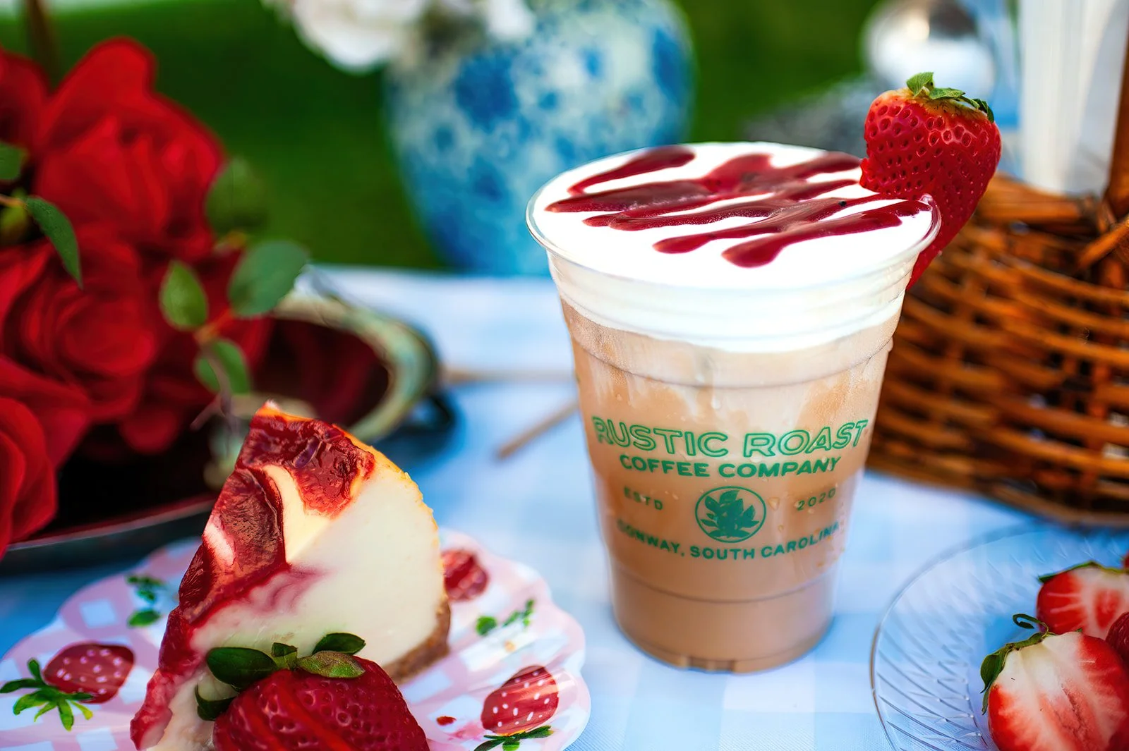 Iced coffee drink with whipped cream, sliced oranges, and blueberries on a wooden surface with greenery in the background.