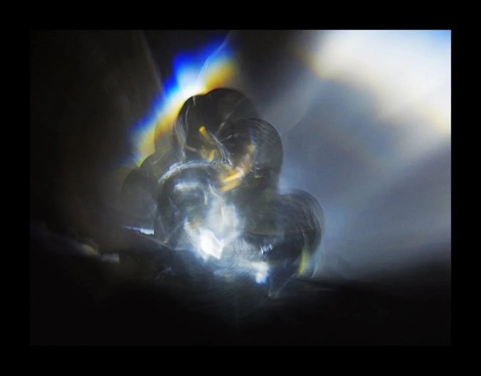 Abstract close-up of a transparent object reflecting colorful light, creating a luminous and iridescent effect.