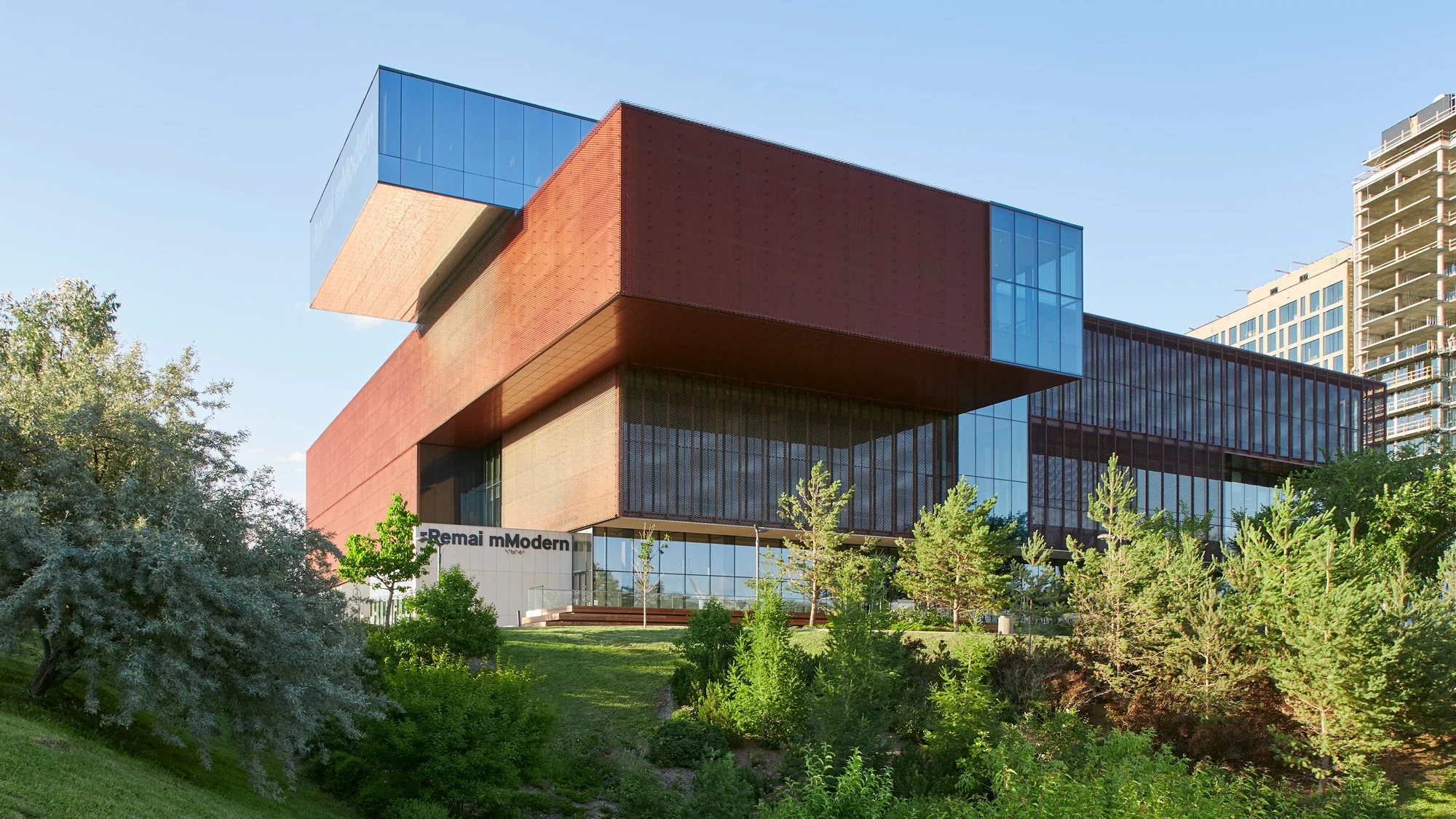 South facade of the Remai Modern Art Gallery in Saskatoon, Saskatchewan. View from across the river. Gallery perched on riverbank above the park.